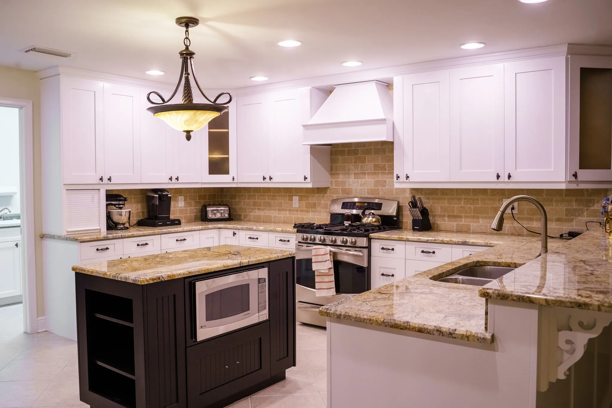 The same Tampa kitchen after painting, with white perimeter cabinets, a dark espresso island and new oil-rubbed bronze hardware